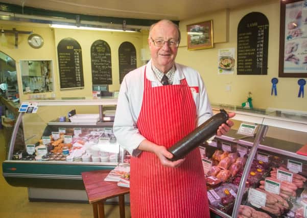 Christopher McCabe at his butchers shop with a black pudding, Picture: SWNS