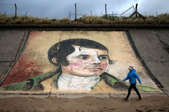 A person walks past a mural of Robert Burns on the sea wall at Ardeer beach, Picture: Jane Barlow/PA Wire