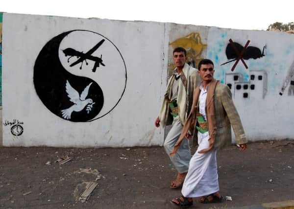 Yemeni men walk past a mural depicting a US drone and a dove in a yin-yang symbol in the capital Sanaa.   picture: MOHAMMED HUWAIS/AFP/Getty Images)