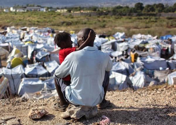 Michelet Louis holds his daughter Youdline, five, while looking over a camp for earthquake survivors in Tabarre, Haiti, in 2010 (Picture)