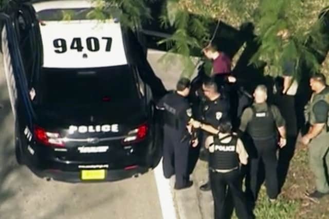 Law enforcement personnel arrest an unidentified man (in dark red), following a shooting at Marjory Stoneman Douglas High School in Parkland. Picture; AP