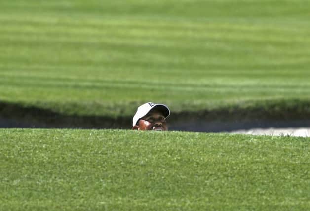 Tiger Woods peers over the lip of a bunker on the first green during the second round of the Genesis Open, where he failed to make the cut. Photograph: Reed Saxon/AP
