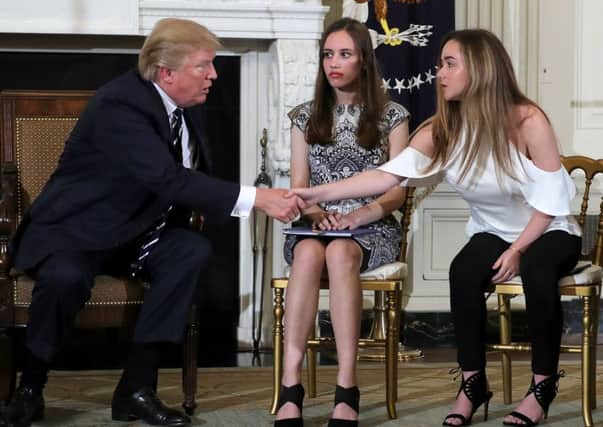 US President Donald Trump (L)  shakes hand with Marjory Stoneman Douglas High School shooting survivors Carson Abt (C) and Ariana Klein at the conclusion of a listening session at the White House. (Photo by Chip Somodevilla/Getty Images)