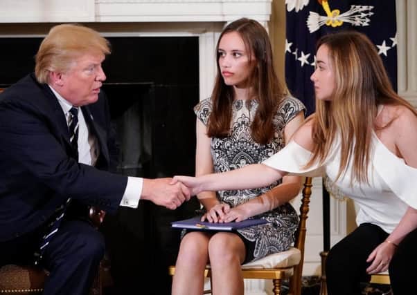 Donald Trump shakes hands with Marjory Stoneman Douglas High School student Ariana Klein, watched by fellow student Carson Abt, at the White House. Picture: Mandel Ngan/Getty