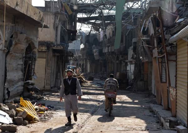 Iraqis walk along a shattered street in war-torn Mosul (Picture: AFP/Getty)
