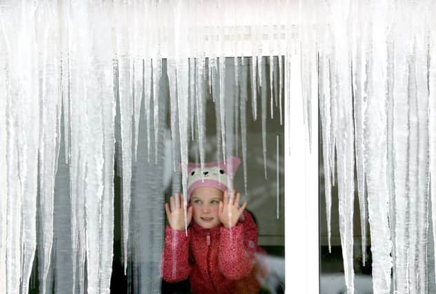 Karis Milligan,6, looks at icicles from the warmth of her grandparents house in Dunblane. Picture: Andrew Milligan/PA Wire