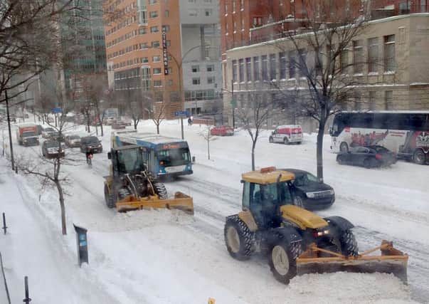 Snowplows remove snow from a downtown avenue in Montreal (Picture: AFP/Getty)