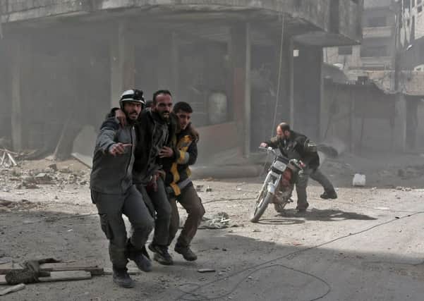 Volunteers from the Syrian civil defence help a man in Hamouria during Syrian government shelling on rebel-held areas in the Eastern Ghouta region in March. Picture: AFP