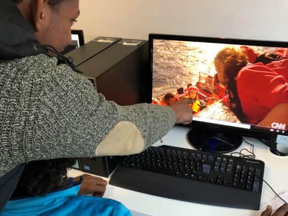 Sonny looks at footage of refugees being rescued from the Mediterranean and recognises a woman who helped him. Picture: Sarah Crowe
