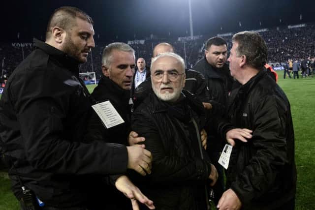 PAOK president Ivan Savvidis (centre) is escorted off the pitch after marching onto the field of play carrying a gun. Picture: AFP