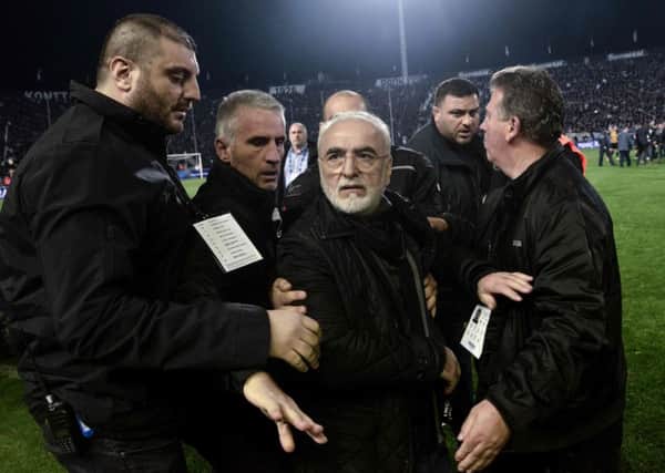 PAOK president Ivan Savvidis (centre) is escorted off the pitch after marching onto the field of play carrying a gun. Picture: AFP