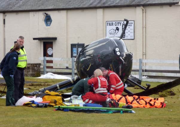 Paramedics treating the pilot of the helicopter which crashed shortly after 10.30am this morning at Perth Airport in Scone. Picture by Graeme Hart/Perthshire Picture Agency