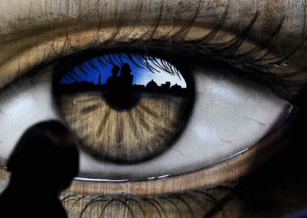 A girl walks past an eye drawn by British street artist My Dog Sighs. Picture: Getty Images