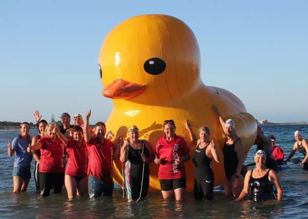 Swimmers posing with Daphne the giant inflatable duck. Pic: Getty
