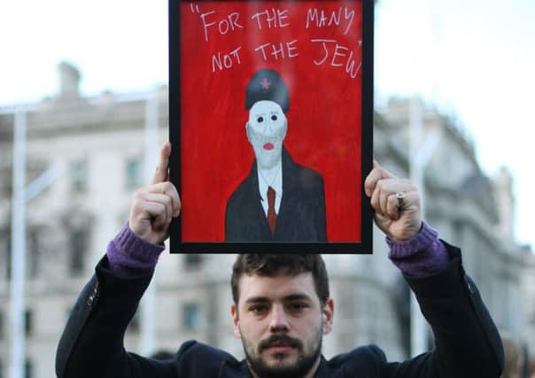 A protester holds a satirical painting at the demonstration in Parliament Square. Picture: 
Yui Mok/PA