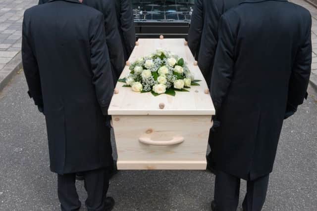 Bearers a carrying a coffin into a car
