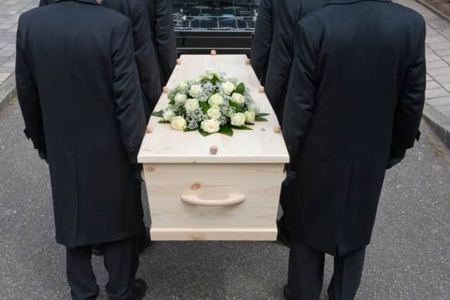 Bearers a carrying a coffin into a car