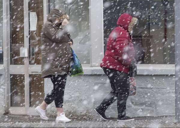 People in Kirkliston near Edinburgh brave the sleet and snow yesterday. Picture: SWNS