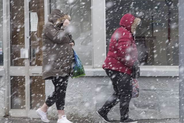People in Kirkliston near Edinburgh brave the sleet and snow yesterday. Picture: SWNS