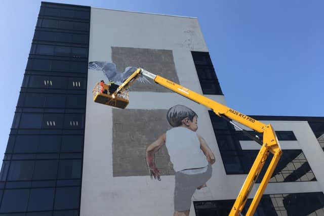Artist Ernest Zacharevic from Lithuania completes his giant work on the side of an Aberdeen office block. PIC: Contributed.
