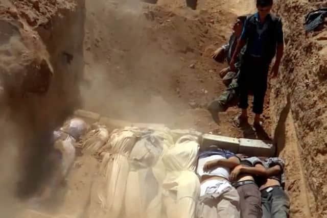 Syrians cover a mass grave containing bodies of victims killed in a toxic gas attack in eastern Ghouta and Zamalka, on the outskirts of Damascus in 2013.
