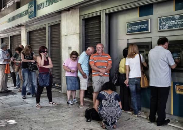 ATHENS, GREECE - JUNE 29: People wait in line to withdraw 60 euros from an ATM after Greece closed its banks on June 29, 2015 in Athens, Greece. Greece closed its banks and imposed capital controls on Sunday to monitor the growing strains on its crippled financial system, bringing the prospect of being forced out of the euro into plain sight.   (Photo by Milos Bicanski/Getty Images)