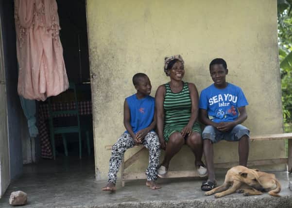 Vilia Odino, 45, outside her hurricane-resistant home in Torbeck, Haiti.  Seen here with her son(s).  Vilia?s home, built by Christian Aid, became shelter to 54 people during Hurricane Matthew in 2016.  When the hurricane hit, her neighbours quickly realised that her house was the only one in the area sturdy enough to survive. She shared food and a safe shelter to sleep for several days.Despite the ferocity of the hurricane, her house lost just one roof panel and wasn?t damaged in any other way. Many of the other homes in the area were totally destroyed. Vilia was given the home by Christian Aid Partner KORAL when she returned to the area after losing her mother and home in the 2010 earthquake in Port Au Prince.  Homeless and with seven children to look after, KORAL reached out to help the family who were clearly vulnerable.  Vilia said: ?I was so happy with the house, I couldn't even wait for them to turn it over to me, it wasn't even done, I went inside, blocked it with sheets and slept inside.? While her h