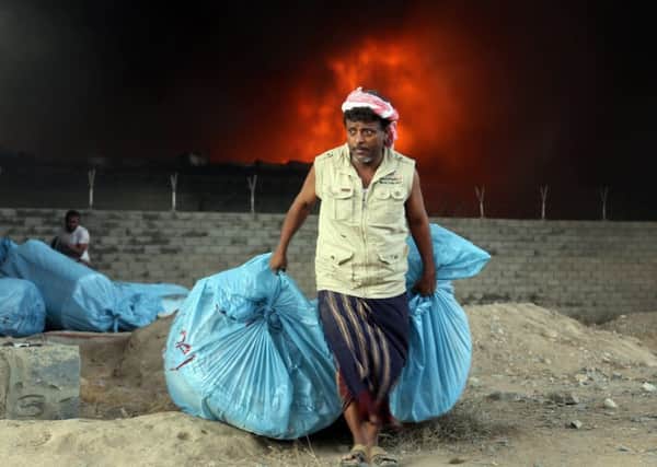 A Yemeni worker saves bags of food as fire engulfs a United Nations warehouse in the coastal town of Hodeida (Picture: AFP/Getty)
