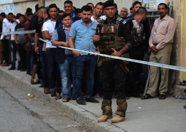 A member of the Iraqi security forces stands guard as people queue in front of a polling station in the Wadi Hajar district of Mosul on May 12, 2018, still partially in ruins from the devastating months-long fight to oust the Islamic State (IS) group. - Iraq began voting in its first parliamentary election since declaring victory over the Islamic State group, with the country hoping to shore up a fragile peace and rebuild.
Polling stations opened around the conflict-scarred nation under tight security as jihadists still pose a major security threat despite a sharp fall in violence. (Photo by AHMAD AL-RUBAYE / AFP) (Photo credit should read AHMAD AL-RUBAYE/AFP/Getty Images)