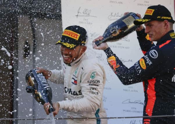 Winner Mercedes driver Lewis Hamilton of Britain sprays champagne, left, flanked by third place Red Bull driver Max Verstappen of the Netherlands, on the podium after the Spanish Formula One Grand Prix at the Barcelona Catalunya racetrack in Montmelo, Spain, Sunday, May 13, 2018. (AP Photo/Emilio Morenatti)