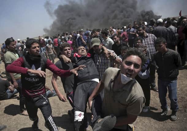 Palestinian protesters carry a man shot by Israeli troops during a protest at the Gaza Strip's border with Israel, east of Khan Younis. (Picture: AP/Khalil Hamra)