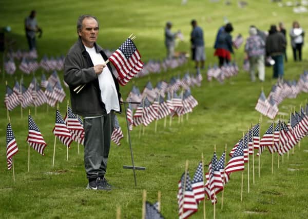 Patrick McCallister, a Vietnam War era army veteran, places flags on the graves of veterans at the Allegheny Cemetery in Pittsburgh ahead of Memorial Day (Picture: AP)