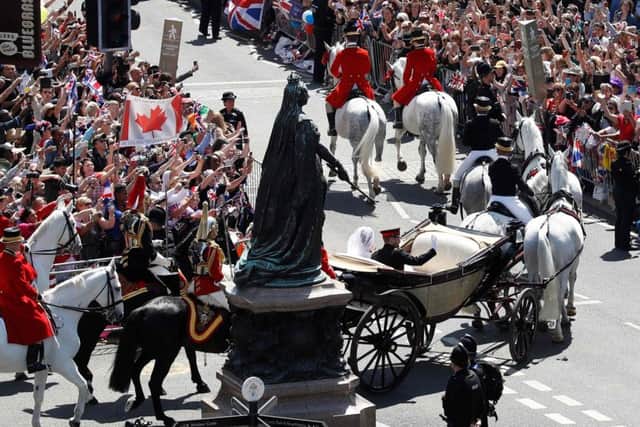 Well-wishers lining the streets wave and cheer as Britain's Prince Harry, Duke of Sussex and his wife Meghan, Duchess of Sussex pass riding in the Ascot Landau Carriage. Picture: AFP/Getty