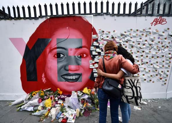 Two women look at bouquets and written notes left on a mural depicting Savita Halappanavar, who died after doctors refused to abort her child. Picture: Charles McQuillan/Getty