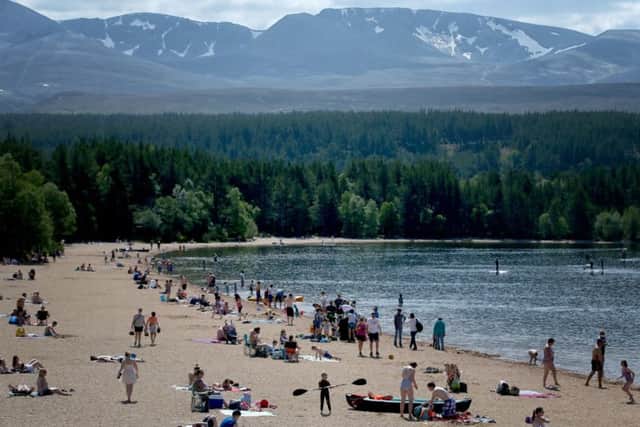 The last few patches of snow remain on the Cairngorms as people enjoy the hot weather on the highest beach in the UK at Loch Morlich near Aviemore. Picture: Jane Barlow/PA Wire