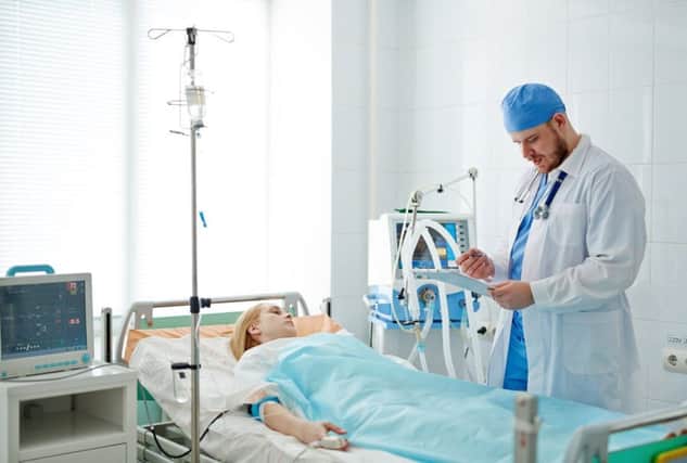 A doctor stands at the bedside of a patient in intensive care