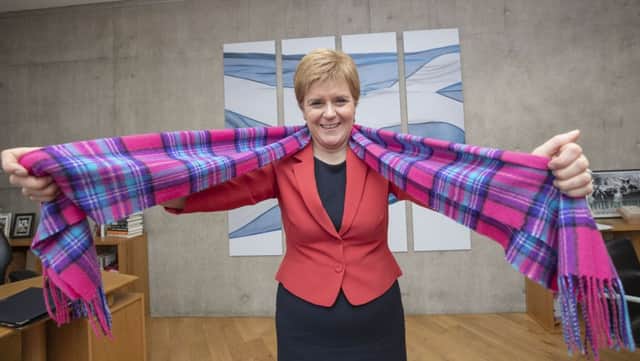 First Minister Nicola Sturgeon models a new pink tartan scarf. The design will be used to raise funds for cancer research