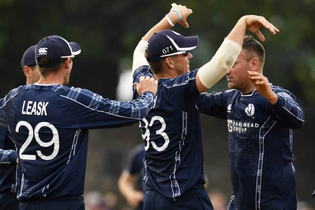 Scotland players celebrate taking the wicket of Moeen Ali during the victory at the Grange. Picture: SNS.