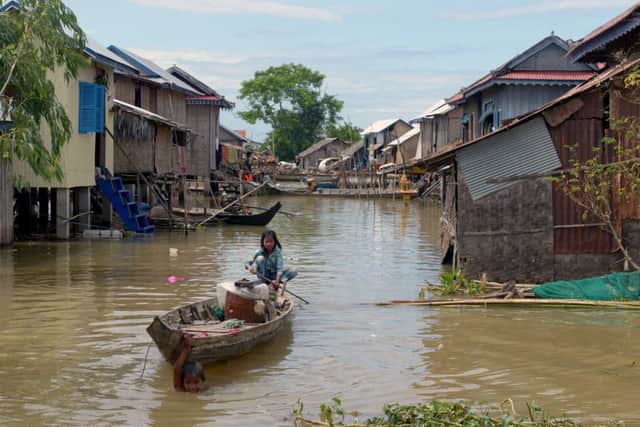 A Cambodian girl rows her boat through flood waters at a village in Kandal province on 2013. More than 80 people died in  floods caused by heavy rains and the Mekong River. Picture: Tang Chhin Sothy/AFP/Getty
