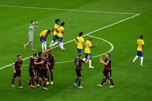 While the Germany players congratulate each other, their Brazilian opponents walk away in humiliation as they succumb to a morale-crushing 7-1 defeat. Picture: Getty