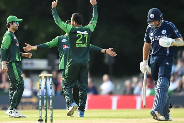Pakistan's Mohammad Nawaz, centre, celebrates aftertaking the wicket of Scotland captain Kyle Coetzer.