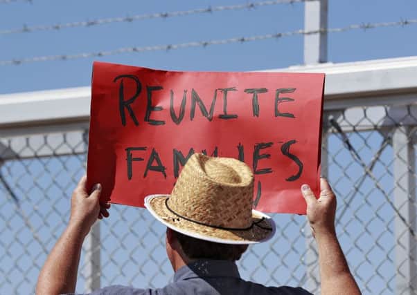 A protester holds a sign outside a closed gate at the Port of Entry facility in Fabens, Texas, where tent shelters are being used to house separated family members. Picture: AP