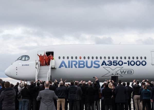 Pilots and crew members wave from the door of an A350-1000 passenger plane, manufactured by Airbus. (Balint Porneczi/Bloomberg via Getty Images)