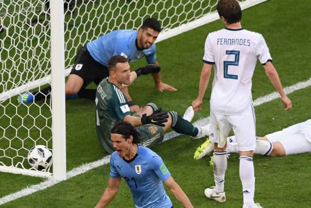 Uruguays Luis Suarez falls into the net as his team-mate Edinson Cavani celebrates making it 3-0. Picture: Getty.