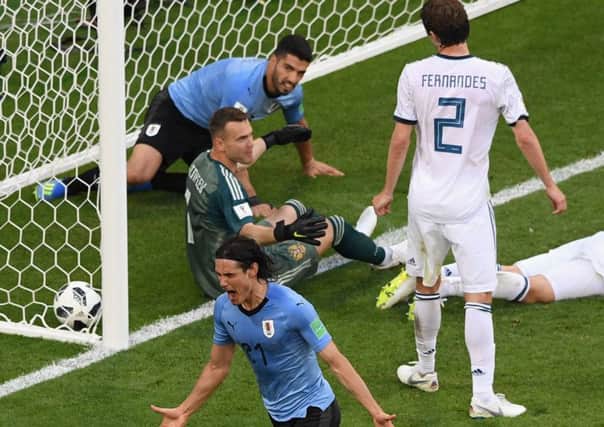 Uruguays Luis Suarez falls into the net as his team-mate Edinson Cavani celebrates making it 3-0. Picture: Getty.