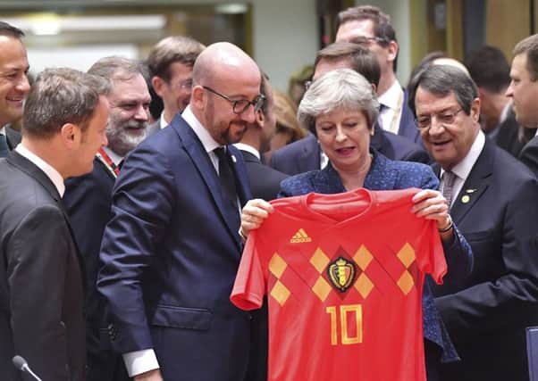 Theresa May holds up a Belgian National team jersey presented by Belgian Prime Minister Charles Michel, center left. Picture: AP Photo/Geert Vanden Wijngaert