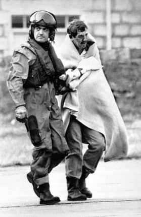 Royal Air Force Air Load Master Bob Pountney helping a survivor as he arrives at Aberdeen Royal Infirmary after the explosion disaster on the North Sea oil production platform Piper Alpha.