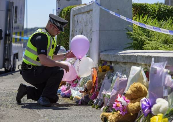 A police officer leaves balloons near a house on Ardbeg Road on the Isle of Bute in Scotland. Picture; PA
