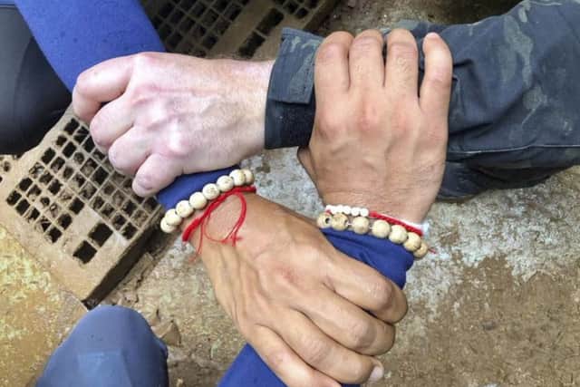 A photo on the Thailand Navy SEAL Facebook page shows rescuers hands locked with a caption reading 'We Thai and the international teams join forces to bring the young Wild Boars home'. Picture: Thailand Navy SEAL Facebook page via AP