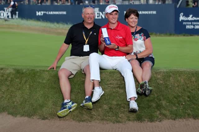 Sam Locke perches on the edge of the 18th green at Carnoustie with his parents and holds his silver medal for finishing best amateur. Picture: Richard Sellers/PA